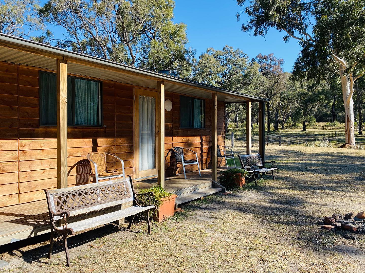 Timber cabin with a covered porch and outdoor seating in the bush surrounding Grey Gum Cafe